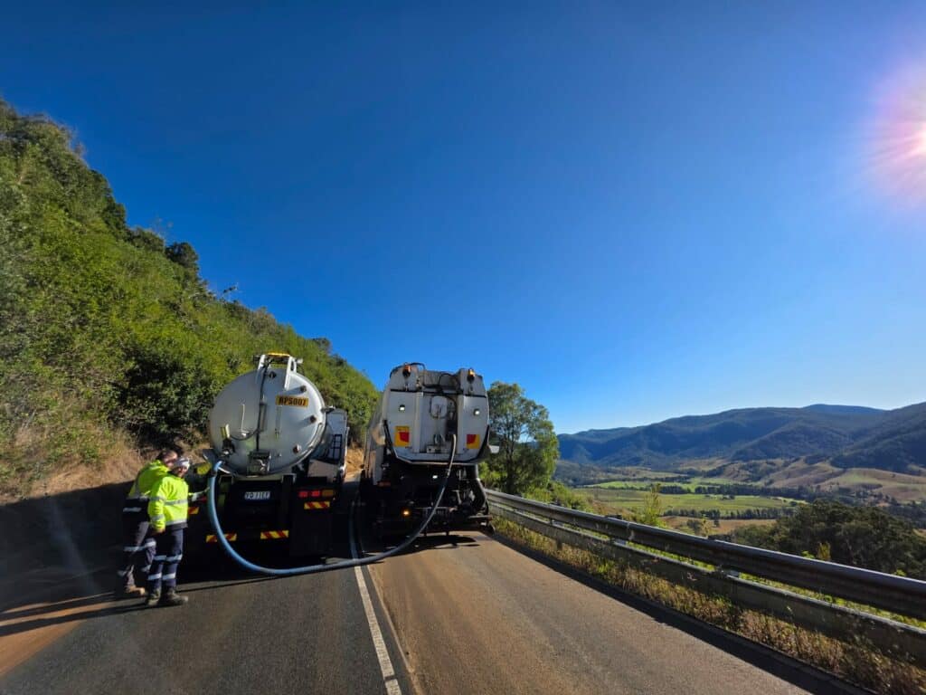 Two trucks and their drivers on the road, at a beautiful landscape